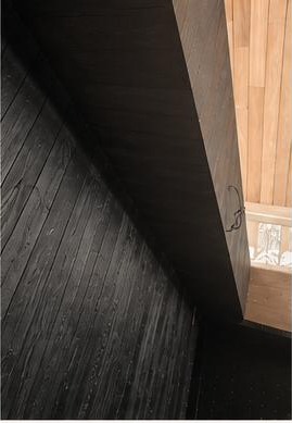 Angled close view of vertical charred-plank rhythm meeting a raw timber wall