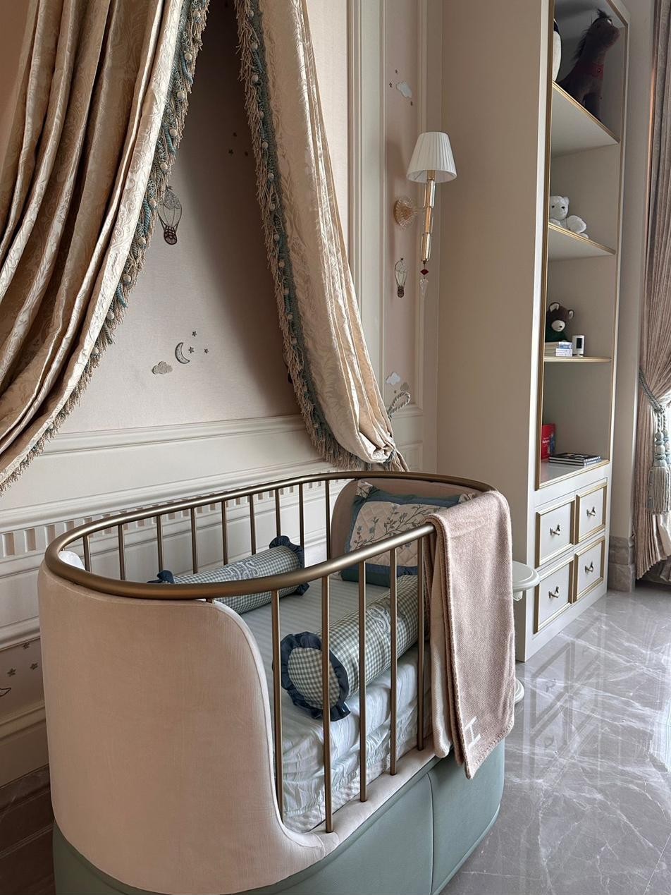Bespoke crib with fabric canopy in a palatial nursery, with gold-toned metallic detailing and fluted rails