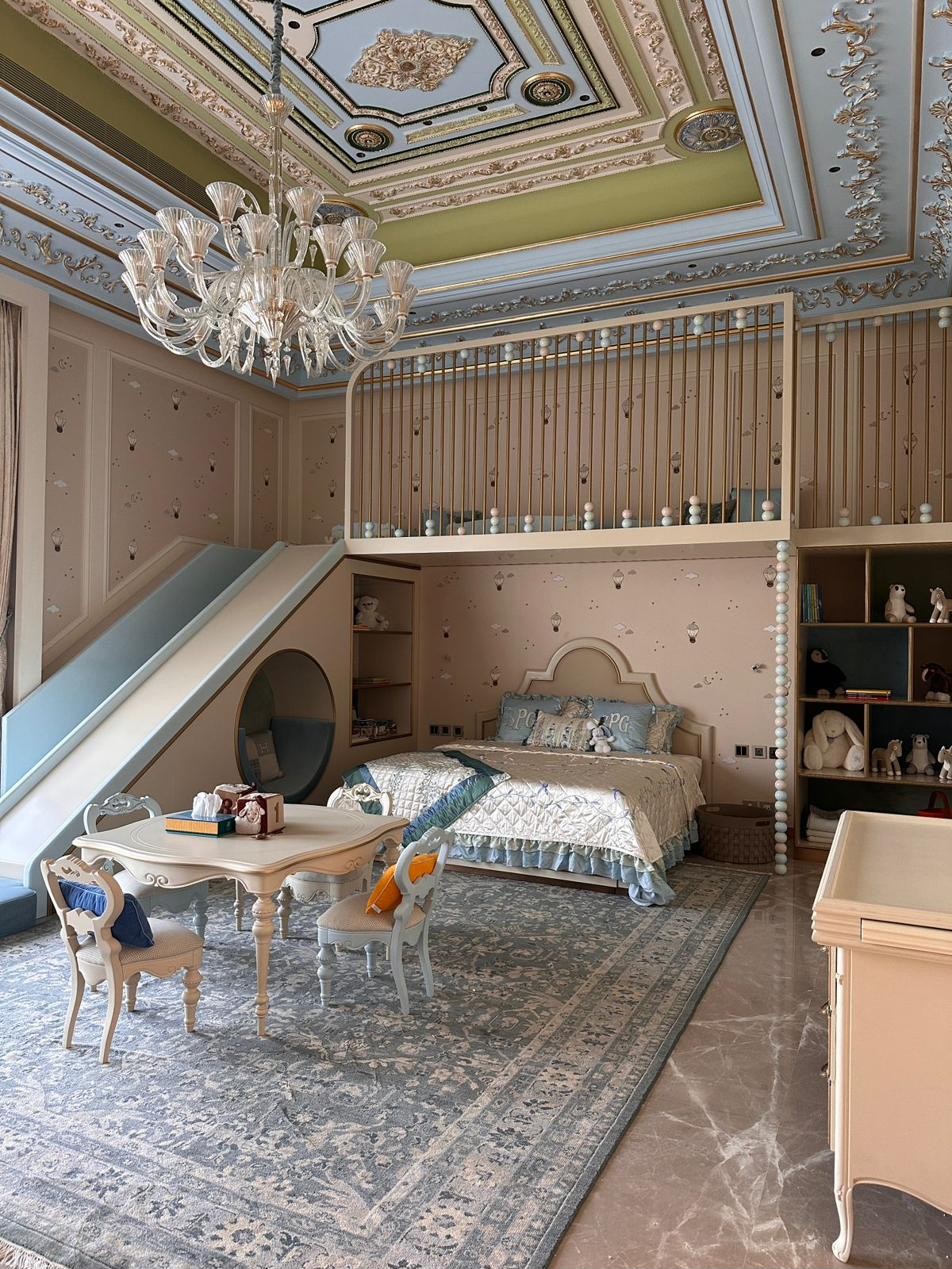 Room overview showing a bed with headboard, elevated loft with slide, chandelier, and open cabinetry